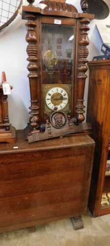 V - A Victorian walnut-cased Vienna wall clock, with heavily carved finial, raised above a 7cm wide...