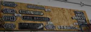V - Various reproduction metal signs, Shell, SS Titanic, etc., on a wooden backing, 122cm wide. NB....