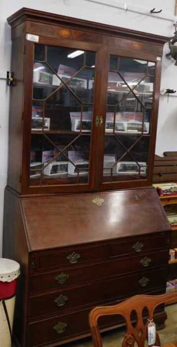 V - A Georgian mahogany bureau bookcase, the fixed cornice with two shell paterae, raised above a...