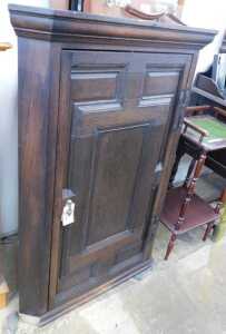V - A 19thC oak stained hanging corner cupboard, the panelled door revealing a fitted interior, with...