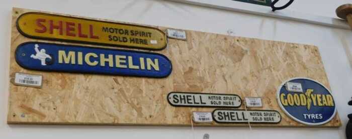 V - Various reproduction signs, Michelin, Shell Motor Spirit, etc., on a wooden backing, 115cm wide....