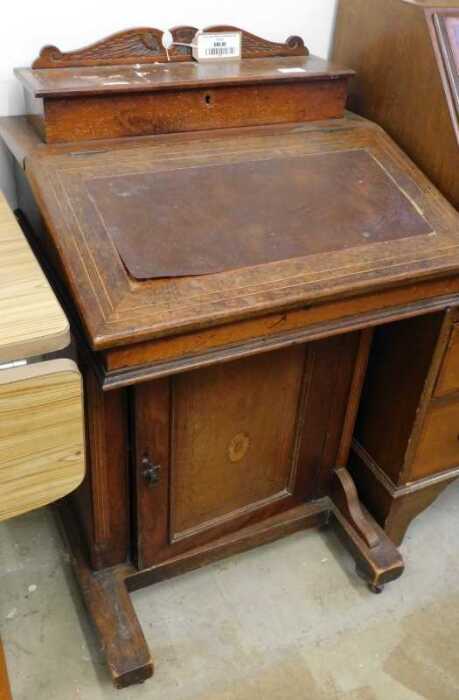 V - An Edwardian walnut Davenport desk, with open back, the fall above cupboard with oval paterae,...