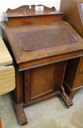 V - An Edwardian walnut Davenport desk, with open back, the fall above cupboard with oval paterae,...