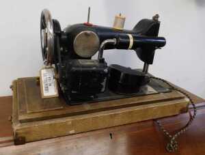 V - A 20thC cased Harris Domestic sewing machine, on a wooden base, with domed case, 46cm wide. NB....