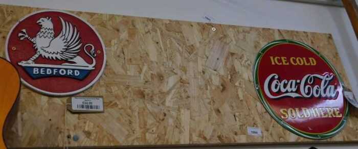 V - Two reproduction signs, for Bedford Lorries and Ice Cold Coca-Cola Sold Here, on a wooden...