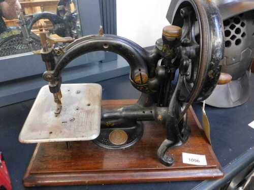 V - A late 19thC Wilcox and Gibbs hand sewing machine, of small proportions, on a wooden base, 33cm...