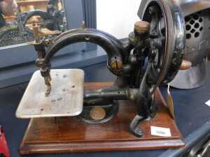 V - A late 19thC Wilcox and Gibbs hand sewing machine, of small proportions, on a wooden base, 33cm...