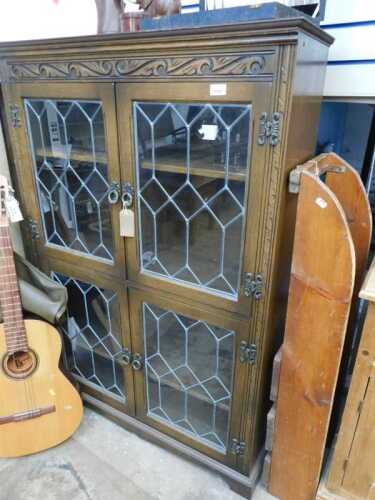 V - An Old Charm-style freestanding bookcase, of rectangular form, with carved top, raised above...