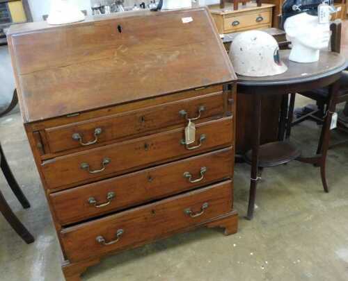 V - An early 20thC mahogany bureau, the fall revealing a part-baize-lined interior, above four long...