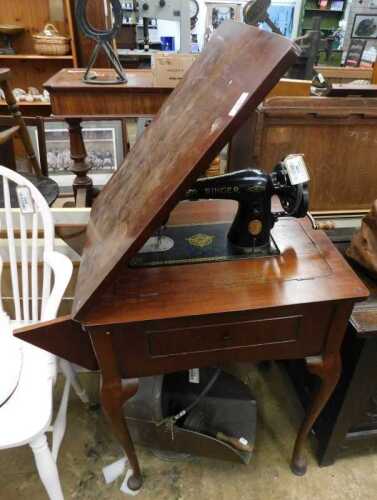 V - An early 20thC Singer sewing machine on stand, with fitted drawer, on cabriole legs terminating...