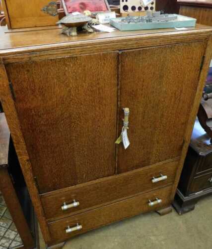 V - A mid 20thC oak cabinet, with a double cupboard, raised above two long drawers, on squat bracket...