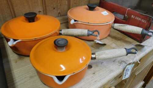 V - Three Le Creuset saucepans, with wooden handles, to include similar-sized pans, and another...