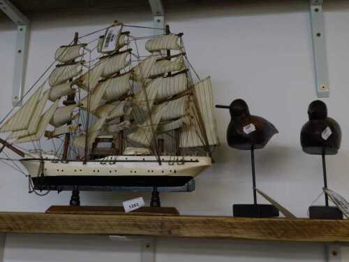 V - A carved model of a boat The Maderia, and two wooden bird figurines, on metal stems with plinth...
