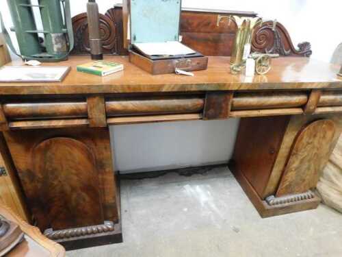 V - A Victorian mahogany pedestal sideboard, with heavily carved back, raised above cushioned frieze...