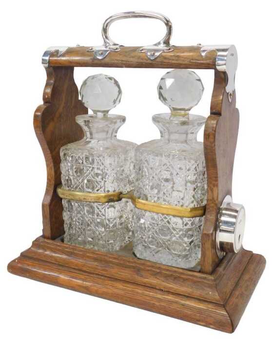 An early 20thC oak and silver mounted twin division tantalus, containing two cut glass square...