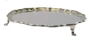 A George V silver salver, of circular form with a piecrust border, raised on three hoof feet,...