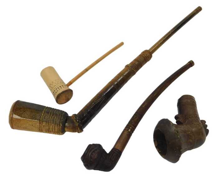 Four Vietnamese Bahnar pipes, each of differing form and decoration, the largest 33cm long....