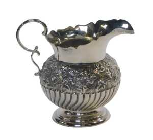 A Victorian silver milk jug, of semi fluted form, decorated with a band of embossed ivy leaves...
