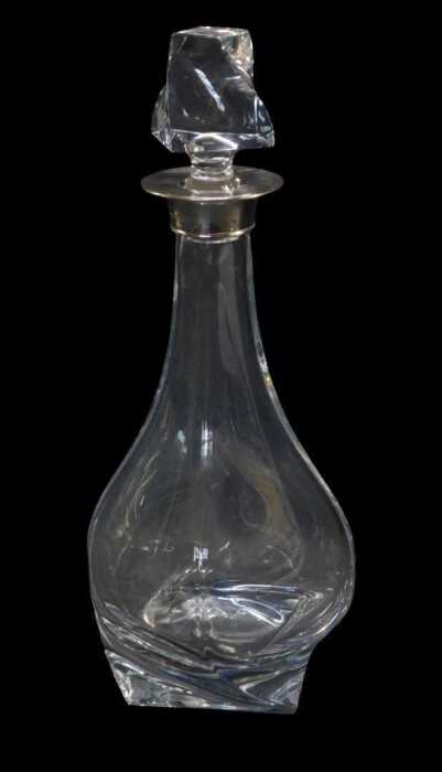An Elizabeth II cut glass decanter with a silver mount, of bottle shaped twisted form, with...