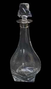 An Elizabeth II cut glass decanter with a silver mount, of bottle shaped twisted form, with...