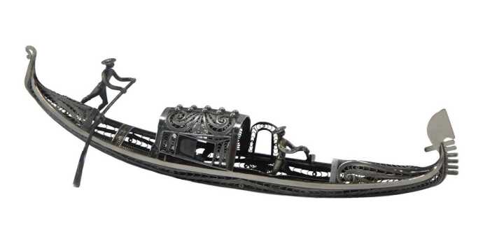A white metal filigree model of a gondola, surmounted by two figures with paddles, white metal...
