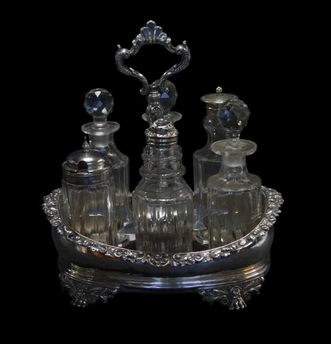 A George IV and later silver cruet stand, of oval form, the border decorated with scrolls and...
