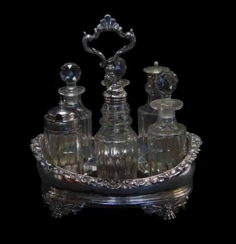 A George IV and later silver cruet stand, of oval form, the border decorated with scrolls and...