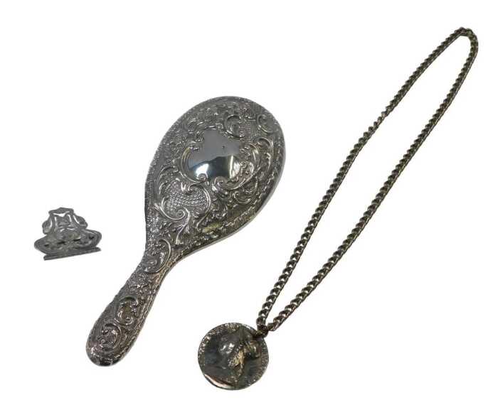 A Victorian silver backed hand mirror, embossed with flower head and scrolling motifs, with a...