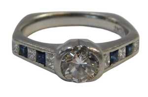 A sapphire and diamond dress ring, with a central round brilliant cut diamond, approx 0.76ct, in...