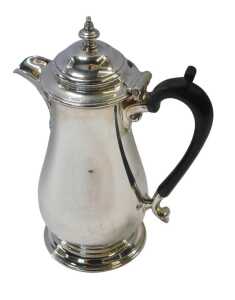 A George V silver hot water jug, of baluster form, with an ebonised handle, raised on a circular...