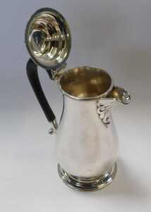 A George V silver hot water jug, of baluster form, with an ebonised handle, raised on a circular... - 2