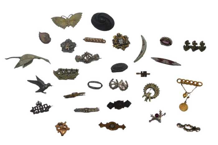 A group of assorted 20thC brooches, comprising mainly plated or base metal examples, crested,...