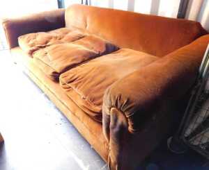 A burnt orange corded velvet upholstered three seater sofa, raised on turned ebonised legs, on...