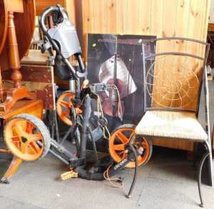 A Click Gear model 3.5+ golf trolley, a cast metal chair, with rush seat, and a picture of a...