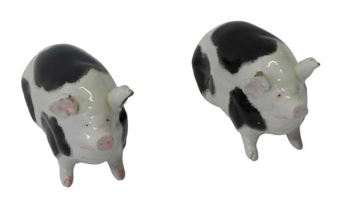 A pair of Wemyss pottery black spotted pigs, in seated position, signed, 9.5cm high. (AF)