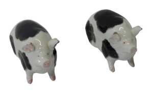 A pair of Wemyss pottery black spotted pigs, in seated position, signed, 9.5cm high. (AF)