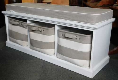A contemporary white finished bench seat, with three bags to three enclosures, raised on plinth...