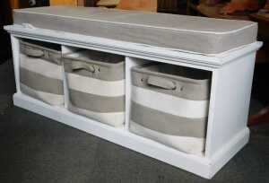 A contemporary white finished bench seat, with three bags to three enclosures, raised on plinth...