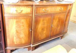A reproduction bow front sideboard, with central drawer over two panelled doors, flanked by two...