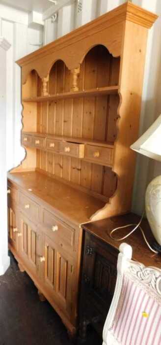 A pine dresser, the top with a moulded pediment above two shelves, with five drawers, the base...