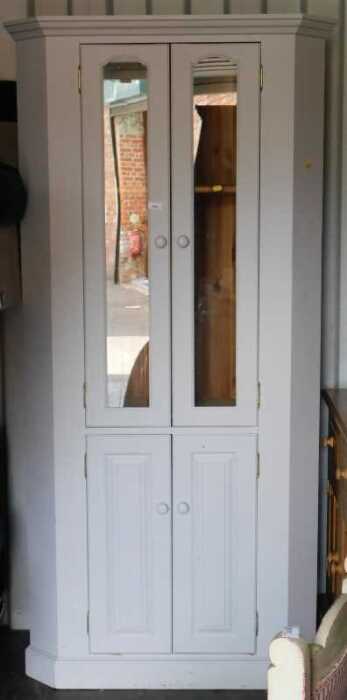 A painted pine corner cabinet, the top with a moulded pediment above two glazed doors to the top...