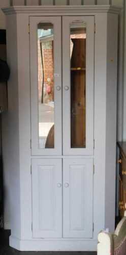 A painted pine corner cabinet, the top with a moulded pediment above two glazed doors to the top...