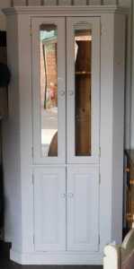 A painted pine corner cabinet, the top with a moulded pediment above two glazed doors to the top...