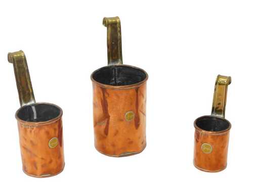 A set of three Victorian graduated copper and brass cream ladles, two pint, one pint, and half...