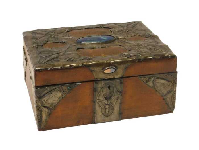 An early 20thC Arts & Crafts sewing box, the hinged lid overlaid with leather and pressed pewter...