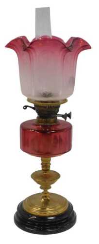 A Victorian brass oil lamp, with a cranberry-tinted etched glass shade, and a cranberry glass...