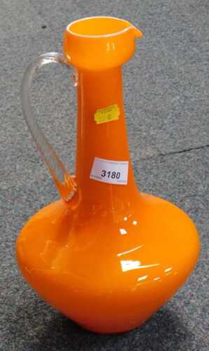 An orange glass ewer, with a twisted clear glass handle, 31cm high.