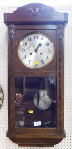 An oak cased wall clock, the circular silvered dial bearing Arabic numerals, with key and...