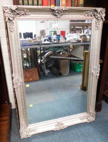 A rectangular wall mirror, in a silvered carved frame, 110cm x 73cm.