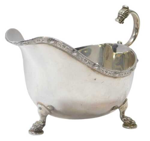 A George VI silver milk jug, with a Celtic design border and open dragon head handle, raised on...